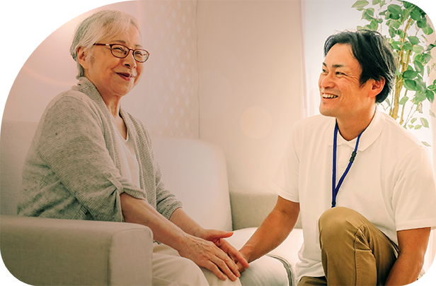 A man places his hand on the knee of an elderly woman, who smiles at the camera